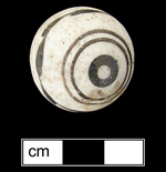 Unglazed porcelain marble with painted bull’s eye motif. Marbles with this type of bull’s eye with a repeating leaf pattern around the circumference have been found in archaeological contexts dating c. 1850-1860 (Carskadden and Gartley 1990) - Click images for larger view.